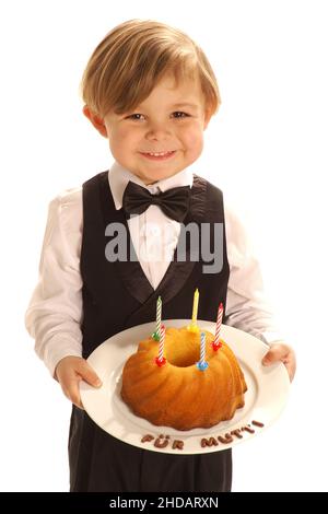 Ein kleiner Junge im Anzug mit einem selbstgebackenen Kuchen für die Mutti, 4 Jahre alt, Model Release vorhanden, Stockfoto