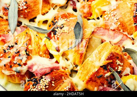 Gebackene Croissants mit Käse, Speck, gekochtem Schweinefleisch und Salbei. Stockfoto