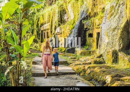 Mutter und Sohn auf dem Hintergrund von Gunung Kawi. Alte geschnitzt in den Steintempel mit königlichen Gräbern. Bali, Indonesien. Reisen mit Kindern Konzept Stockfoto