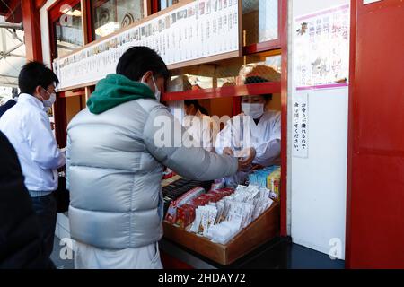 Tokio, Japan. 5th Januar 2022. Mitarbeiter, die eine schützende Gesichtsmaske tragen, verkaufen Glücksbringer im Kanda Myojin-Schrein. Viele Unternehmen schicken am 4. Und 5. Januar, den ersten Arbeitstagen des Jahres, Arbeiter in den Schrein, um für das Glück im Geschäft zu beten. (Bild: © Rodrigo Reyes Marin/ZUMA Press Wire) Stockfoto