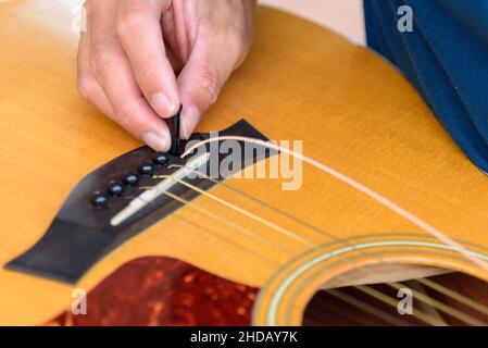 Der Musiker ersetzt die neuen Gitarrensaiten für seine Gitarre Stockfoto