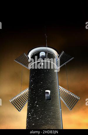 Silhouette einer Windmühle und eines Leuchtturms in der dunklen Nacht. Stockfoto