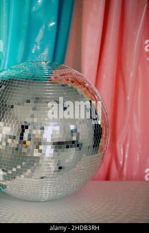 Große glänzende reflektierende Spiegel silber funkelnden Nachtleben Disco Ball vor farbenfrohem Hintergrund reflektiert helle Lichter, vertikale Aufnahme. Party-Design Stockfoto