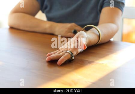 Ausgeschnittene Aufnahme einer reifen Frau, die ihre Handfläche dem Geisterbeschwörer oder Palmist zeigt, um Lebenslinien, Handlesen und Vorhersagen über zukünftige Entwicklungen zu lesen Stockfoto