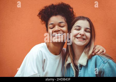 Portrait von zwei fröhlichen Teenagern verschiedener Rassen, die vor der Kamera lächeln und Freundschaft genießen, multiethnische beste Freundinnen, die Selfie phot machen Stockfoto