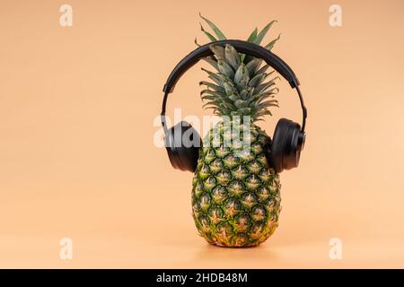 Interpretation von Ananasfrüchten in einem menschlichen Bild mit Kopfhörern für das Hören von Musik Konzept der Entspannung und Entspannung im Urlaub. Stockfoto