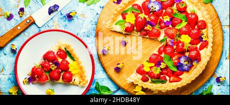 Erdbeerkuchen in Scheiben, verziert mit essbaren Blumen und Minze.Trendy Summer Berry Pie Stockfoto