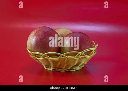 Rote Äpfel im Korb auf rotem Hintergrund Stockfoto