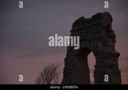 Fotos, die bei Sonnenuntergang bei einem Spaziergang durch den wunderschönen Aquädukt-Park in Rom mit den majestätischen Ruinen der antiken römischen Aquädukte und Bäume aufgenommen wurden Stockfoto