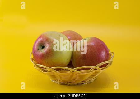 Äpfel im Korb auf gelbem Hintergrund Stockfoto