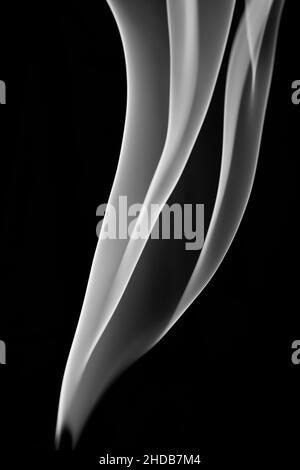 Hübsche Muster von Rauchspuren aus Weihrauch auf schwarzem Hintergrund Stockfoto