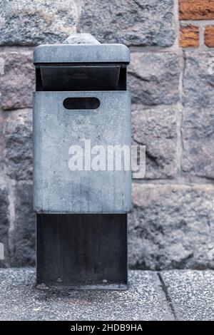 Frontansicht des öffentlichen Abfallbehälters aus Metall mit integriertem Aschenbecher oben. Vertikal. Tag. Selektiver Fokus... Stockfoto