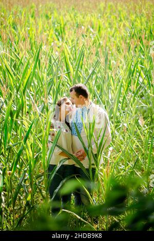 Junges Paar in ukrainischen Hemden auf einem Feld mit Mais Stockfoto