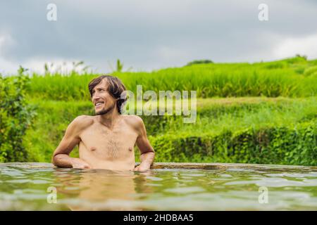 Man Tourist in Belulang Hot Springs auf Bali auf dem Hintergrund von Reisterrassen Stockfoto