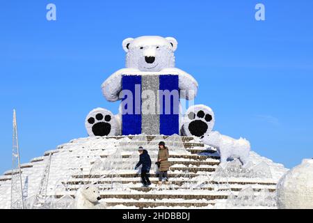 Ein festliches Weihnachtsspielzeug großer Eisbär steht auf einer Stadtstraße im Winter wandern die Menschen zwischen den Neujahrsdekorationen. Dnipro City Stockfoto