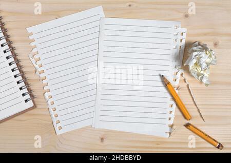 Saubere Blätter von Notizbuch, gebrochenem Bleistift und zerknittertem Papier vor dem Hintergrund eines Holztisches, Draufsicht Stockfoto