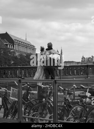 Vertikale Graustufenaufnahme eines Paares, das auf einer Brücke in Kopenhagen, Dänemark, steht Stockfoto