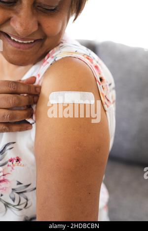 Glückliche ältere Frau, die nach der Impfung einen Haftverband am Arm zeigt Stockfoto