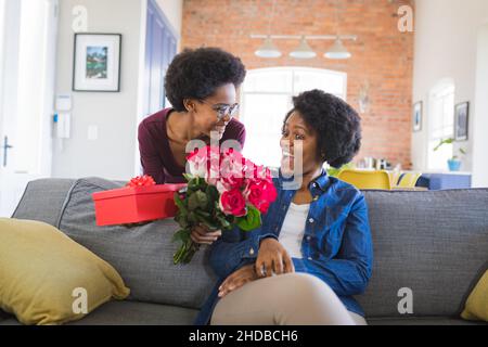 Überraschung Mutter von Tochter Geschenk und Rosenstrauß während Geburtstag zu Hause Stockfoto