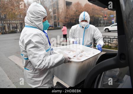 (220105) -- XI'AN, 5. Januar 2022 (Xinhua) -- Freiwillige transportieren Lebensmittel auf ein Auto, um sie im Bezirk Yanta von Xi'an, nordwestlich der chinesischen Provinz Shaanxi, zu liefern, 4. Januar 2022. Deshan, eine Gemeinschaftsküche im Bezirk Yanta von Xi'an, wurde als „krebsbekämpfende Küche“ geführt und bietet Krebspatienten und ihren Familien die Möglichkeit, Mahlzeiten zuzubereiten. Xu Kai, der Gründer der Gemeinschaftsküche, verwandelte diese „krebsbekämpfende Küche“ in eine „Kampf-gegen-Epidemie-Küche“, nachdem die Stadt vor kurzem vom Wiederaufleben des COVID-19 getroffen wurde. Bisher haben sich mehr als 30 Freiwillige an der Lebensmittelzustellung angeschlossen Stockfoto