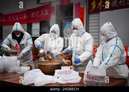 (220105) -- XI'AN, 5. Januar 2022 (Xinhua) -- Freiwillige verpacken Lebensmittel für die Lieferung in der Gemeinschaftsküche Deshan im Bezirk Yanta in Xi'an, nordwestlich der chinesischen Provinz Shaanxi, 4. Januar 2022. Deshan, eine Gemeinschaftsküche im Bezirk Yanta von Xi'an, wurde als „krebsbekämpfende Küche“ geführt und bietet Krebspatienten und ihren Familien die Möglichkeit, Mahlzeiten zuzubereiten. Xu Kai, der Gründer der Gemeinschaftsküche, verwandelte diese „krebsbekämpfende Küche“ in eine „Kampf-gegen-Epidemie-Küche“, nachdem die Stadt vor kurzem vom Wiederaufleben des COVID-19 getroffen wurde. Bisher haben sich mehr als 30 Freiwillige dem Food Delive angeschlossen Stockfoto