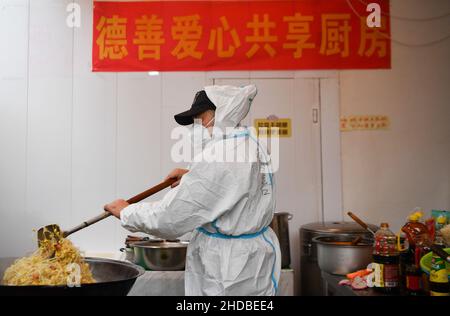 (220105) -- XI'AN, 5. Januar 2022 (Xinhua) -- der Freiwillige Li Guang stellt in der Gemeinschaftsküche Deshan im Bezirk Yanta in Xi'an, nordwestlich der chinesischen Provinz Shaanxi, Geschirr für die Lieferung her, 4. Januar 2022. Deshan, eine Gemeinschaftsküche im Bezirk Yanta von Xi'an, wurde als „krebsbekämpfende Küche“ geführt und bietet Krebspatienten und ihren Familien die Möglichkeit, Mahlzeiten zuzubereiten. Xu Kai, der Gründer der Gemeinschaftsküche, verwandelte diese „krebsbekämpfende Küche“ in eine „Kampf-gegen-Epidemie-Küche“, nachdem die Stadt vor kurzem vom Wiederaufleben des COVID-19 getroffen wurde. Bisher haben sich mehr als 30 Freiwillige dem Essen angeschlossen Stockfoto