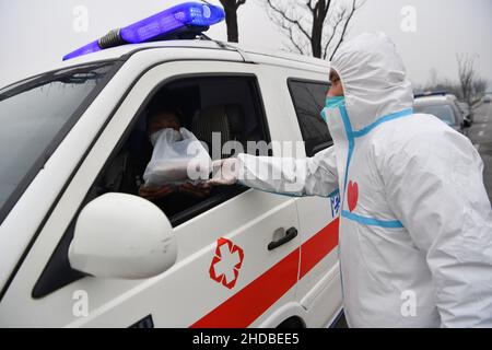 (220105) -- XI'AN, 5. Januar 2022 (Xinhua) -- der Freiwillige Chang Lin liefert einem Krankenwagen-Fahrer im Bezirk Yanta in Xi'an, nordwestlich der chinesischen Provinz Shaanxi, Lebensmittel, am 4. Januar 2022. Deshan, eine Gemeinschaftsküche im Bezirk Yanta von Xi'an, wurde als „krebsbekämpfende Küche“ geführt und bietet Krebspatienten und ihren Familien die Möglichkeit, Mahlzeiten zuzubereiten. Xu Kai, der Gründer der Gemeinschaftsküche, verwandelte diese „krebsbekämpfende Küche“ in eine „Kampf-gegen-Epidemie-Küche“, nachdem die Stadt vor kurzem vom Wiederaufleben des COVID-19 getroffen wurde. Bisher haben sich mehr als 30 Freiwillige der Lebensmittelzustellung angeschlossen Stockfoto