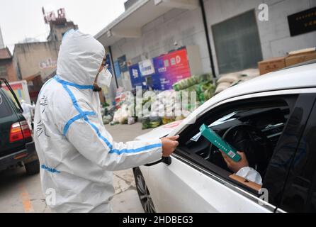 (220105) -- XI'AN, 5. Januar 2022 (Xinhua) -- Xu Kai gibt einem Freiwilligen im Yanta Bezirk Xi'an, nordwestlich der chinesischen Provinz Shaanxi, Gesichtsmasken, 5. Januar 2022. Deshan, eine Gemeinschaftsküche im Bezirk Yanta von Xi'an, wurde als „krebsbekämpfende Küche“ geführt und bietet Krebspatienten und ihren Familien die Möglichkeit, Mahlzeiten zuzubereiten. Xu Kai, der Gründer der Gemeinschaftsküche, verwandelte diese „krebsbekämpfende Küche“ in eine „Kampf-gegen-Epidemie-Küche“, nachdem die Stadt vor kurzem vom Wiederaufleben des COVID-19 getroffen wurde. Bisher haben sich mehr als 30 Freiwillige an den Aktivitäten zur Lebensmittelzustellung des Kits angeschlossen Stockfoto