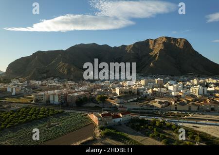 Luftaufnahme der Stadt Callosa de Segura. Drohne Sicht spanisches Dorf am Fuße des riesigen felsigen Berges Sierra de Callosa. Nordwesten Stockfoto