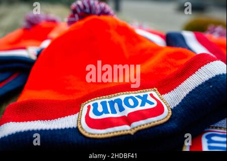 Ein Blick auf die traditionellen orangefarbenen Beanies von Unox auf einem Holztisch. Diese Woche ist es genau 25 Jahre her, dass das letzte Elfstedentocht-Event (eine fast 200 Kilometer lange Langstrecken-Tour-Skating-Veranstaltung auf Natureis) stattfindet. Es war auch der Tag, an dem die Niederlande erstmals die orangene Eislaufmütze aus Unox kennenlernten. Im Laufe der Jahre wurden Hunderttausende von Unox-Beanies während Winterveranstaltungen an Besucher und Teilnehmer verteilt, wie zum Beispiel beim traditionellen Neujahrstauchen am Strand von Scheveningen, was diese niederländische Stilikone zu einem unverzichtbaren Teil des Bildes des Winters in T macht Stockfoto