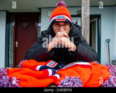 Nijmegen, Gelderland, Niederlande. 3rd Januar 2022. Ein Mann posiert mit einer traditionellen orangen Beanie von Unox. Diese Woche ist es genau 25 Jahre her, dass das letzte Elfstedentocht-Event (eine fast 200 Kilometer lange Langstrecken-Tour-Skating-Veranstaltung auf Natureis) stattfindet. Es war auch der Tag, an dem die Niederlande erstmals die orangene Eislaufmütze aus Unox kennenlernten. Im Laufe der Jahre wurden Hunderttausende von Unox-Beanies während Winterveranstaltungen an Besucher und Teilnehmer verteilt, wie zum Beispiel beim traditionellen Neujahrstauchgang am Strand von Scheveningen, was diese niederländische Stilikone zu einem Indispensabl macht Stockfoto