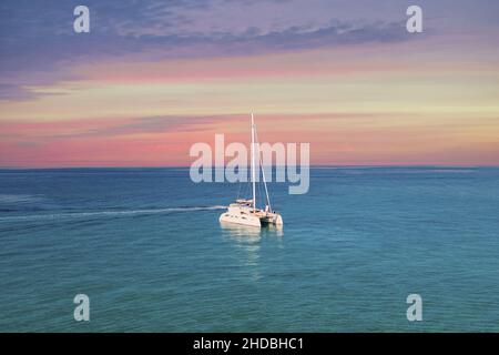 Yacht, die auf dem Mittelmeer Griechenlands driftet und das Boot versteckt, wobei die schaumige Spur unter blauem wolkenlosem Himmel am Horizont zurückbleibt Stockfoto