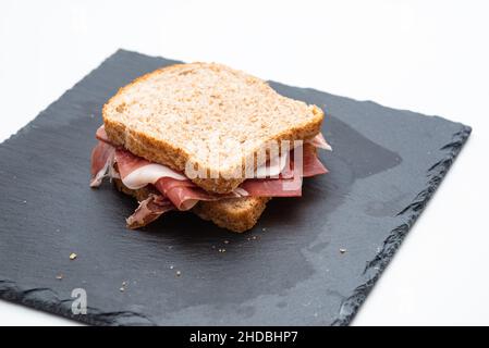 Vollkornbrot-Sandwich mit rohem Schinken und Salat auf weißem Hintergrund Stockfoto