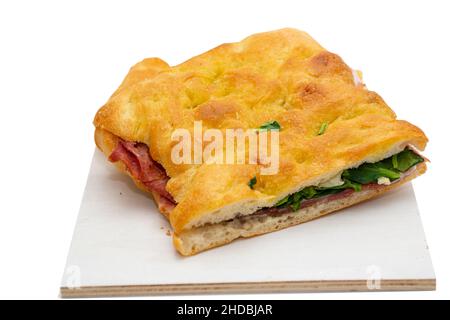 Focaccia gefüllt mit Prosciutto und Salat auf Holz Schneidebrett, isoliert auf weißem Hintergrund Stockfoto