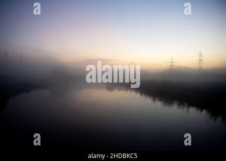 Wilhelmshaven, Deutschland. 21st Dez 2021. Dichter Nebel hängt kurz vor Sonnenaufgang über der Maade im Bezirk Heppenser Groden. Quelle: Hauke-Christian Dittrich/dpa/Alamy Live News Stockfoto