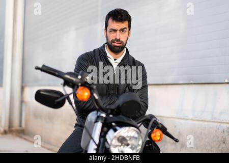 Trauriger junger Mann auf einem Motorrad Stockfoto
