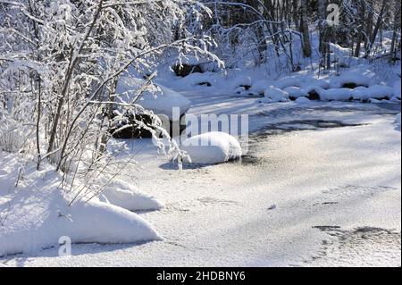 Winterlandschaft mit Schnee bedeckt Bäume auf zugefrorenen Fluss. Stockfoto