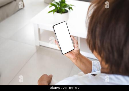 Ältere Frau, die Smartphone mit Kopierplatz im Wohnzimmer zu Hause benutzt Stockfoto