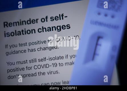 Eine positive laterale Durchflusstestkassette, die neben Empfehlungen der NHS COVID-App auf einem iPhone in London platziert wird. Die britische Gesundheitsbehörde hat gesagt, dass Menschen in England ohne Coronavirus-Symptome, die einen positiven lateralen Flow-Test haben, ab Januar 11 keinen bestätigenden PCR-Test mehr benötigen. Bilddatum: Mittwoch, 5. Januar 2022. Stockfoto