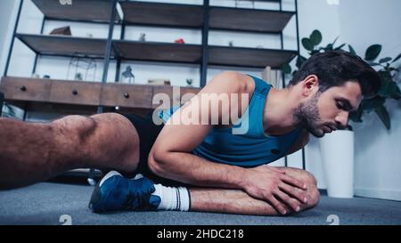Junger Sportler im Tank Top Stretching zu Hause Stockfoto