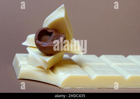Weiße Schokoladenstücke und Milchschokolade-Praline, in die gebissen Stockfoto