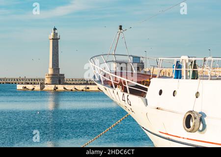 Bug von alten Fischerboot verankert und schönen Leuchtturm im Hintergrund mit blauen ruhigen Wasser Meer Stockfoto