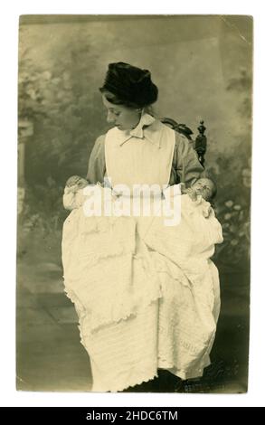 Originalpostkarte aus der frühen Edwardianischen Ära mit attraktivem Kindermädchen in gestärkter Schürzenkleid mit Zwillingen in weißen Taufkutten, Foto von J.L. Clark, Blyth, Northumberland. Ca. 1902 Stockfoto