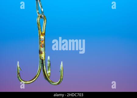 Nahaufnahme eines Angelhakens aus Metall mit einem Hintergrund in blau-violetter Farbe Stockfoto