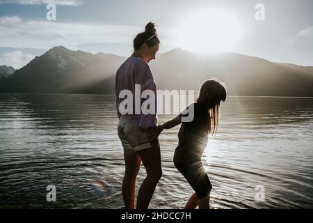 Schwestern stehen an einem sonnigen Tag am Ufer eines Sees Stockfoto