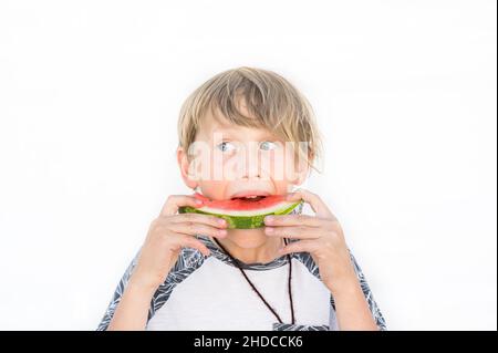 Pre teen junge im Alter von 9 essen reife Wassermelone Scheibe mit weißem Hintergrund Stockfoto