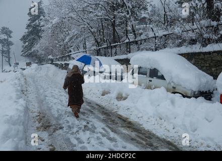 Srinagar, Indien. 5th Januar 2022. Eine Kashmiri-Frau kommt an dem Fahrzeug vorbei, das während des starken Schneefalls in Tangmarg, westlich von srinagar Kaschmir, vergraben wurde. Die nationale Autobahn Srinagar-Jammu, die einzige Straßenverbindung, die Valley mit dem Rest der Welt verbindet, wurde wegen des Verkehrs geschlossen, während neun Flüge ebenfalls aufgrund der schlechten Wetterbedingungen in Jammu und Kaschmir gestrichen wurden, da am Mittwoch der zweite Tag in Folge starker Schneefall anhielt. (Bild: © Sajad Hameed/Pacific Press via ZUMA Press Wire) Stockfoto