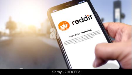 Rom, Italien, Januar 2022: Hand hält ein Smartphone mit der mobilen Reddit-App auf dem Bildschirm auf einem städtischen Hintergrund. Reddit ist eine amerikanische Social News A Stockfoto