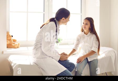 Lächelnde Kinderärztin im Gespräch mit einem glücklichen Mädchen nach ihrer medizinischen Untersuchung in der Klinik Stockfoto