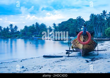 Faszinierende Szene von Holzbooten im lila Wasser auf den Inseln in Batam, Indonesien bei Sonnenuntergang Stockfoto